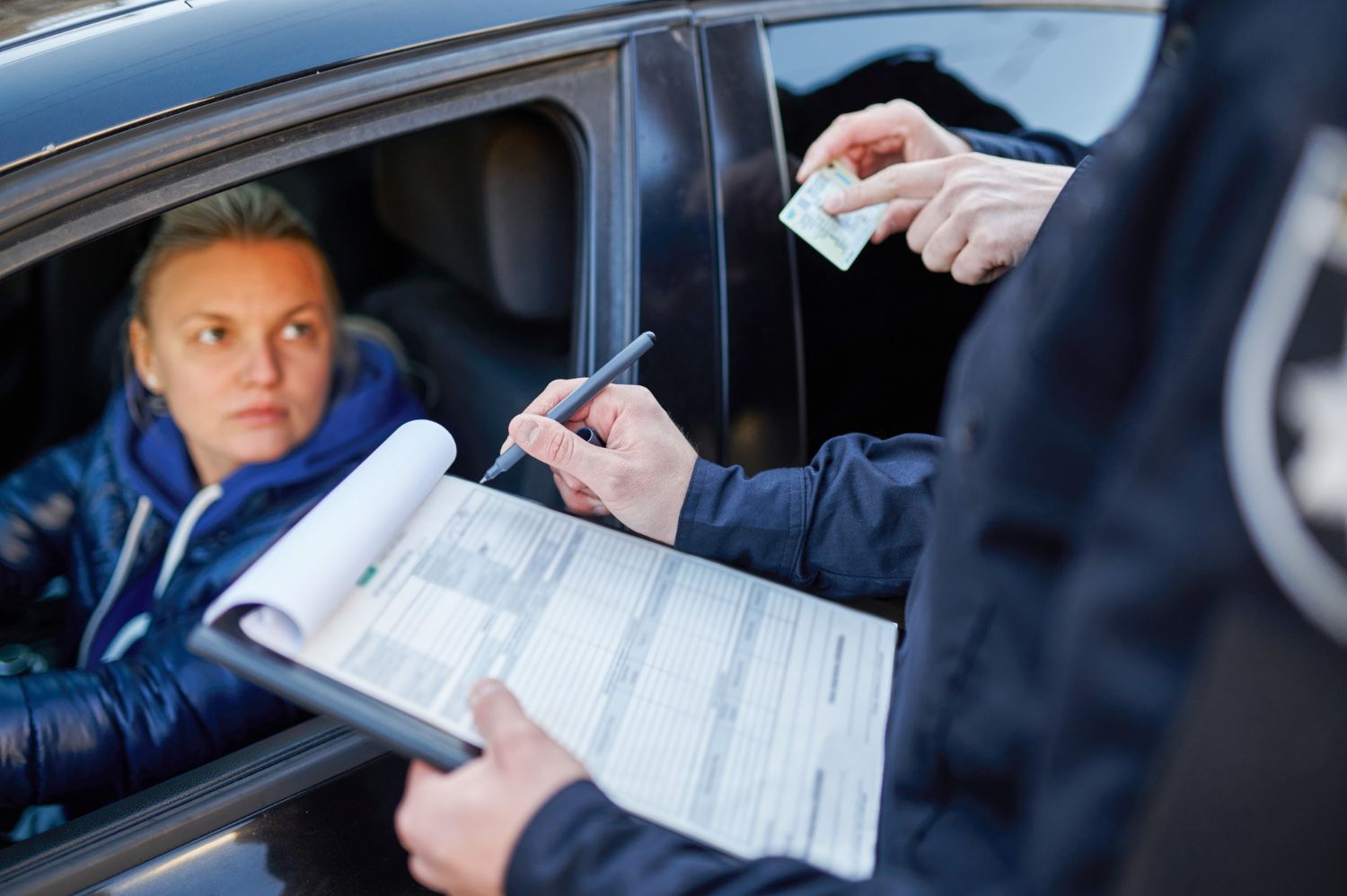 An officer writes on a clipboard during a traffic stop