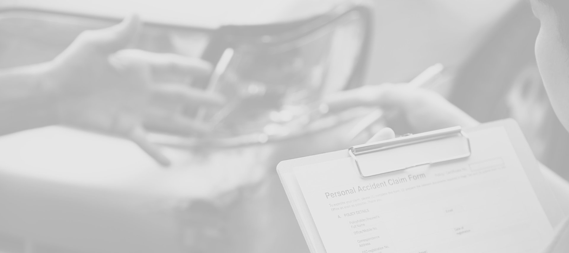 A desaturated image shows a person holding a clipboard with a "Personal Accident Claim Form."