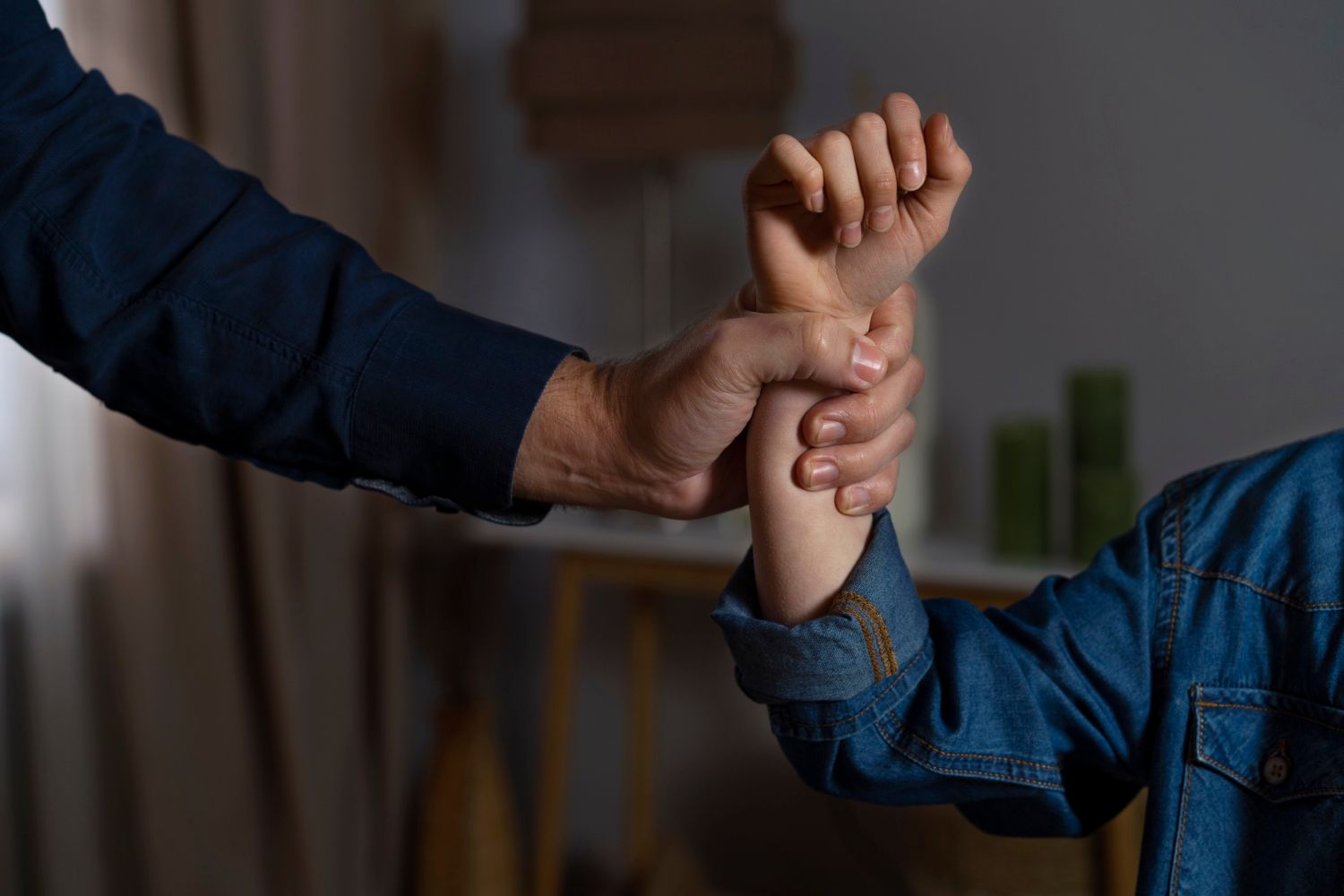 An adult's hand firmly grips a child's wrist, symbolizing force or abuse