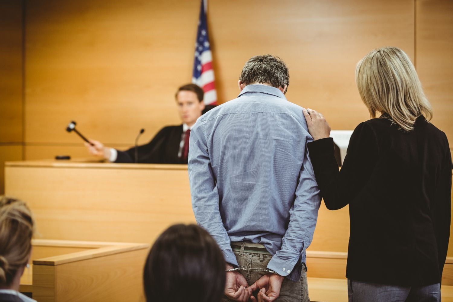 A man in handcuffs stands in a courtroom