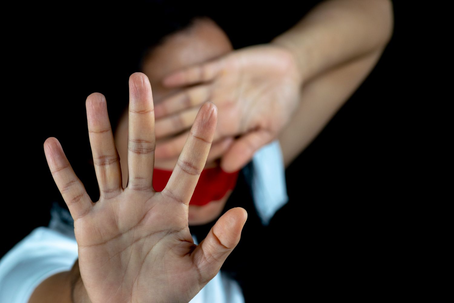 A person holds their hands up to block their face