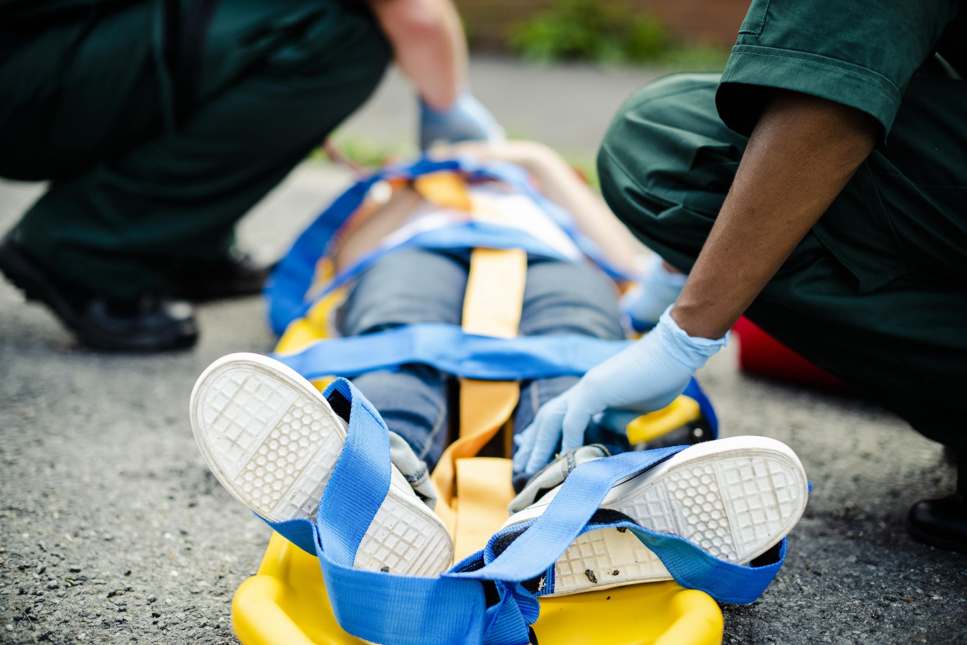 Emergency responders attend to an injured person strapped to a yellow stretcher