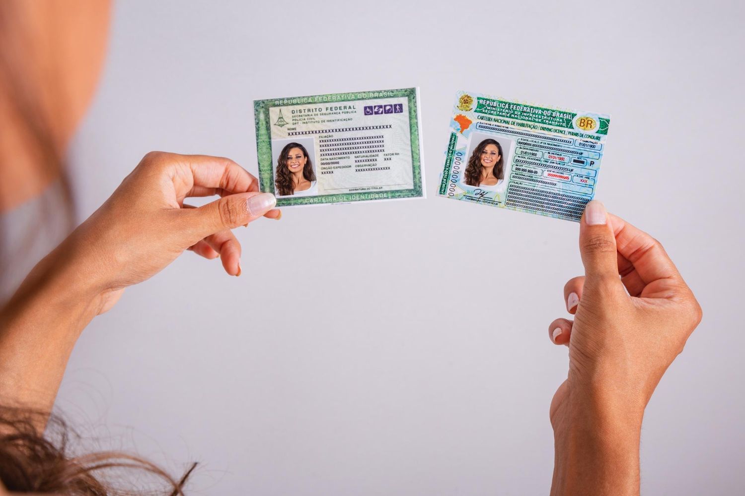 Two hands display a Brazilian ID card and driver's license